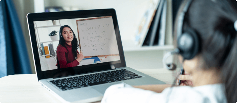 A tutor teaching two students in a classroom.