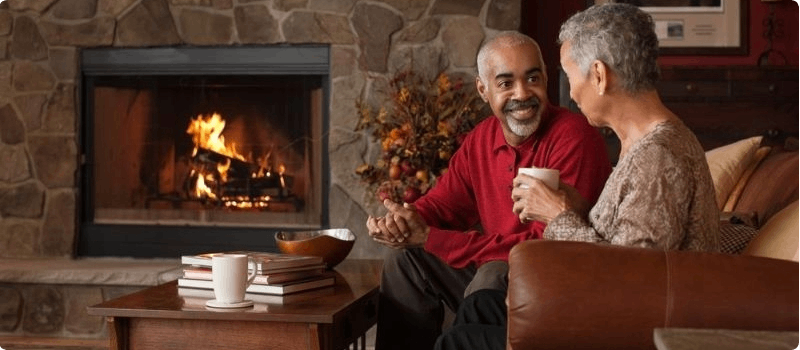 Happy couple sitting in front of fireplace.