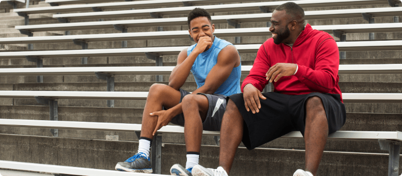 A mentor sitting on steps laughing with their mentee.