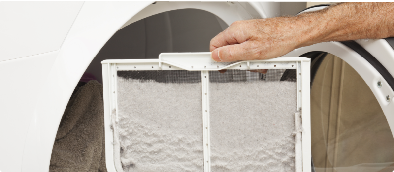 Hand holding a dryer lint filter covered with lint