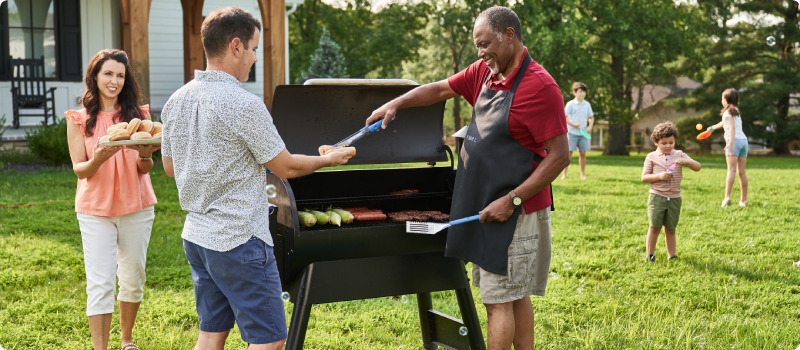 Older man grilling and passing food out