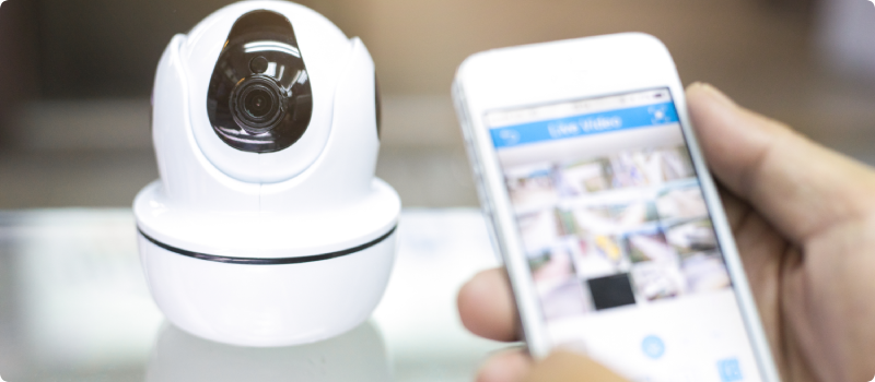 Security camera and hand holding a smartphone