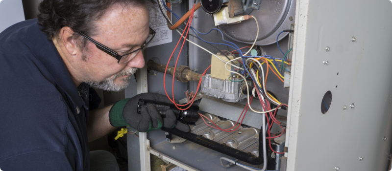 A close-up of a HVAC repair person fixing a furnace.