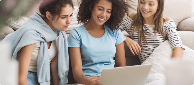 Female roommates surfing internet on laptop.