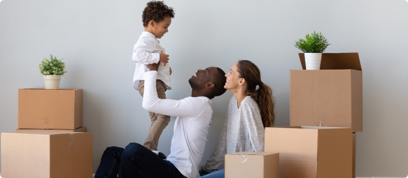 Happy parents with their son next to packed moving boxes