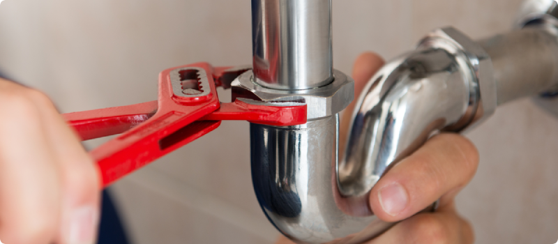 Closeup Of Plumber Fixing Pipe With Wrench