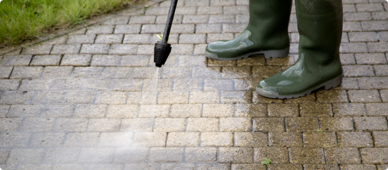 a person power washing a driveway