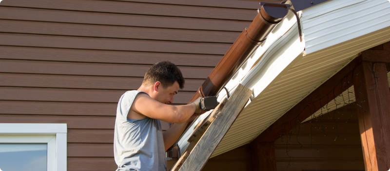 man working on a home's gutters