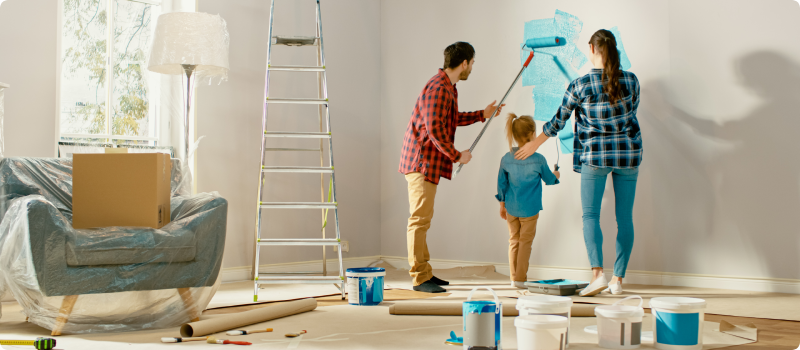 Parents painting wall with daughter