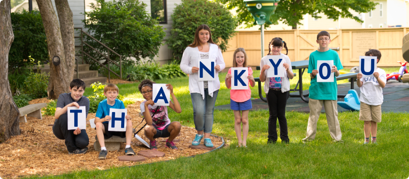 people holding signs spelling "thank you"