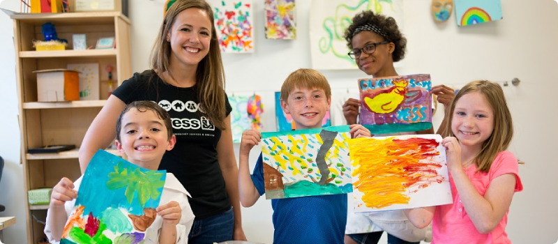 a woman with kids holding paintings