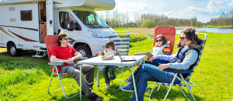 a family of four sitting outside an RV