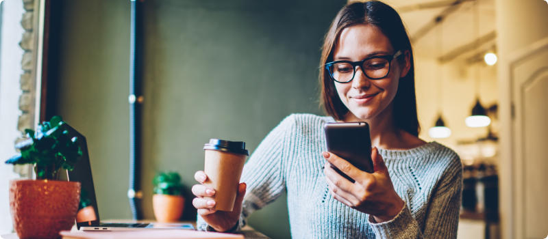 Woman on her smartphone with coffee in hand