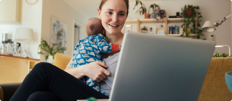 a woman working on a laptop while holding a baby