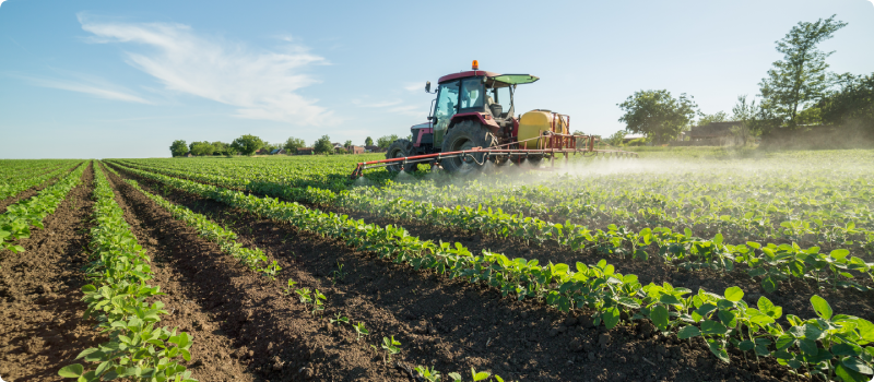 Tractor spraying field with pesticides and herbicides