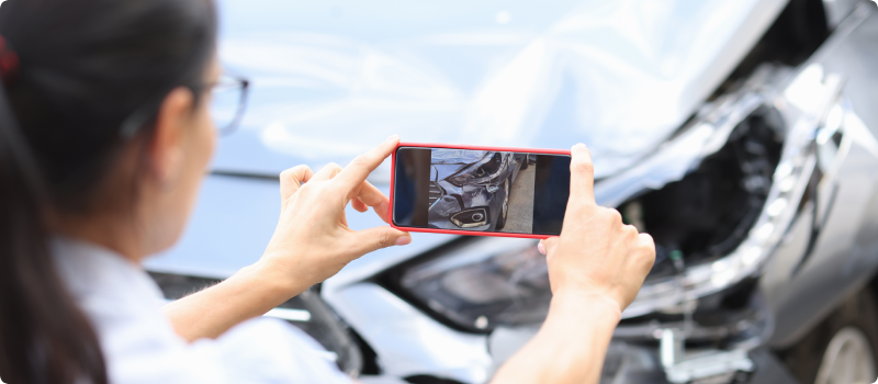 a woman taking a photo of the damage to her car