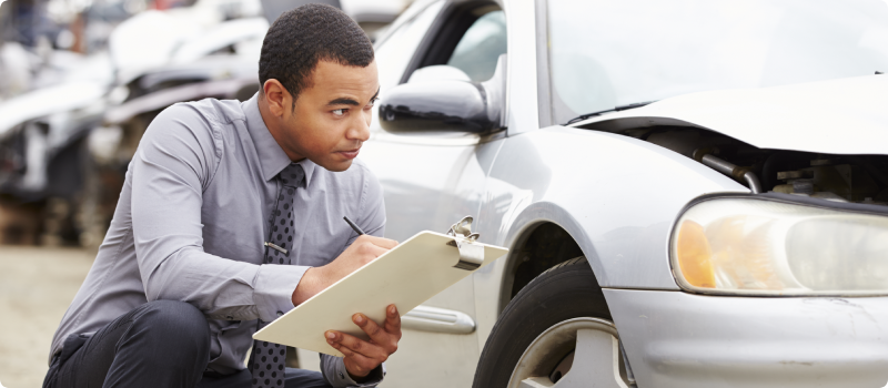 Insurance adjuster inspecting car after an accident