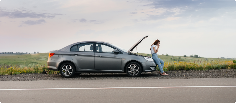 a person stranded by the side of the road with their car