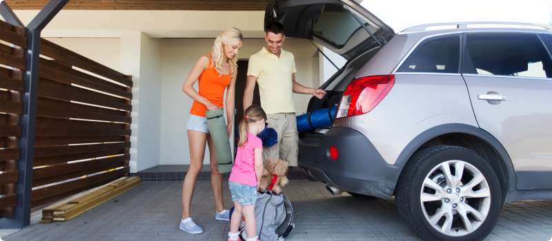 Family loading items into car for a road trip.