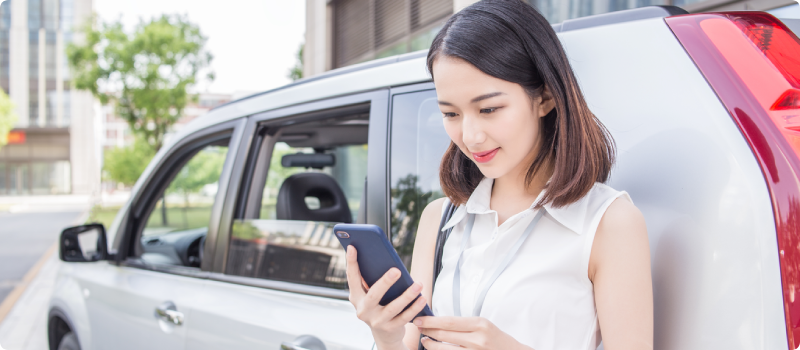 a woman looking at her phone while leaning against a car