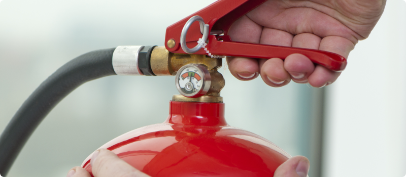 Hand pressing trigger on a fire extinguisher