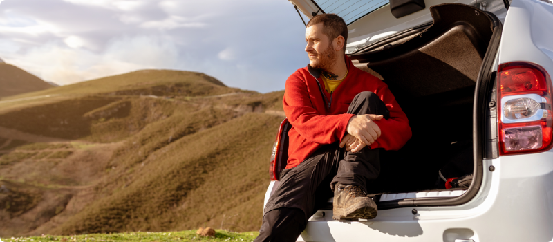 a man sitting in the back of his car looking at mountains