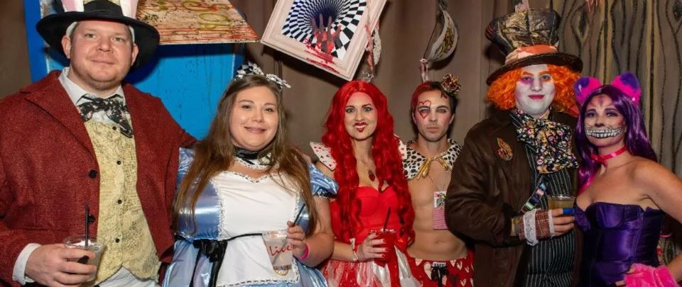 Group of six people dressed as Alice in Wonderland characters at Ballpark Village's Halloween party in St. Louis.