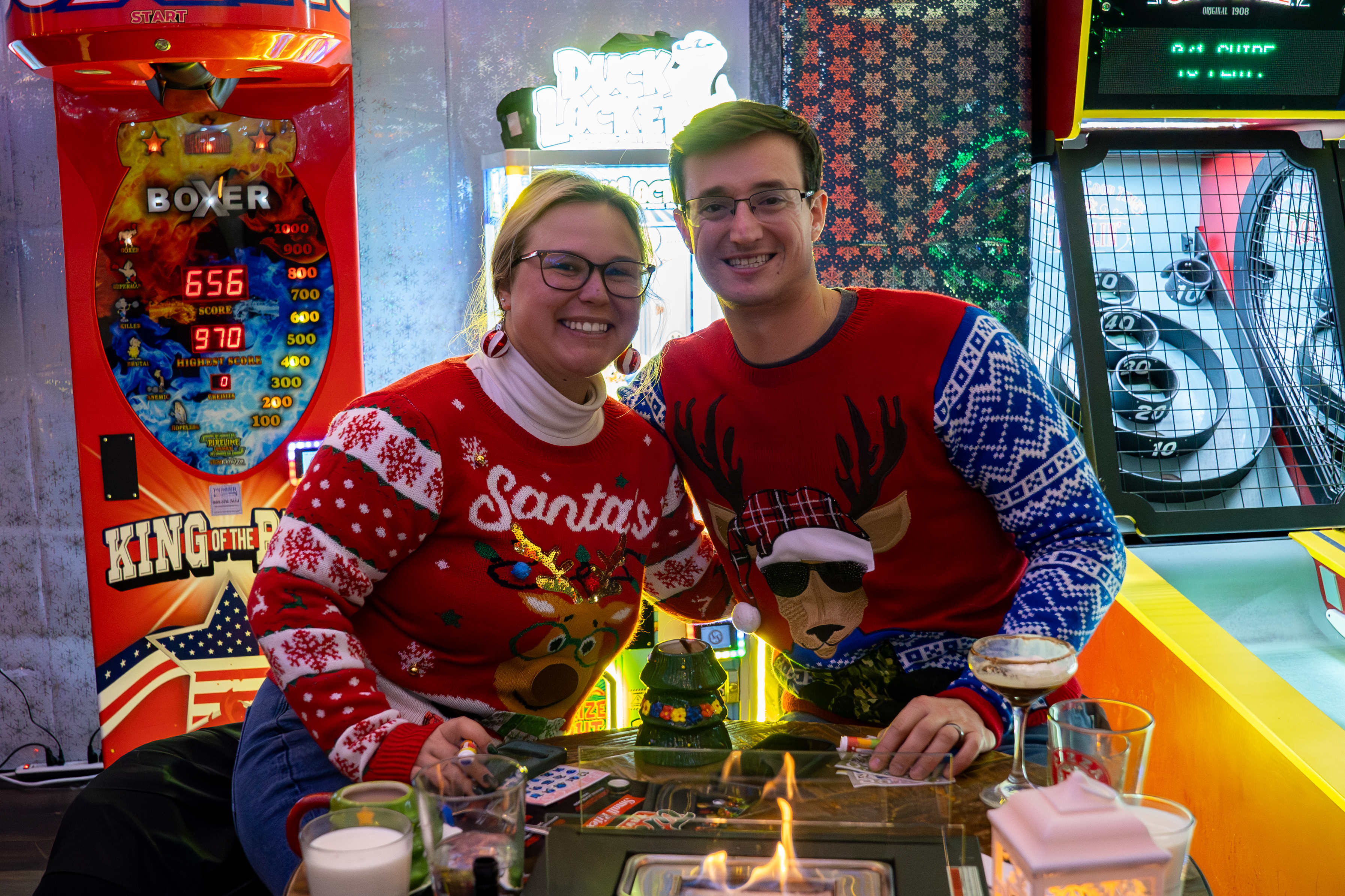 A couple posing for a pic in Christmas sweaters.