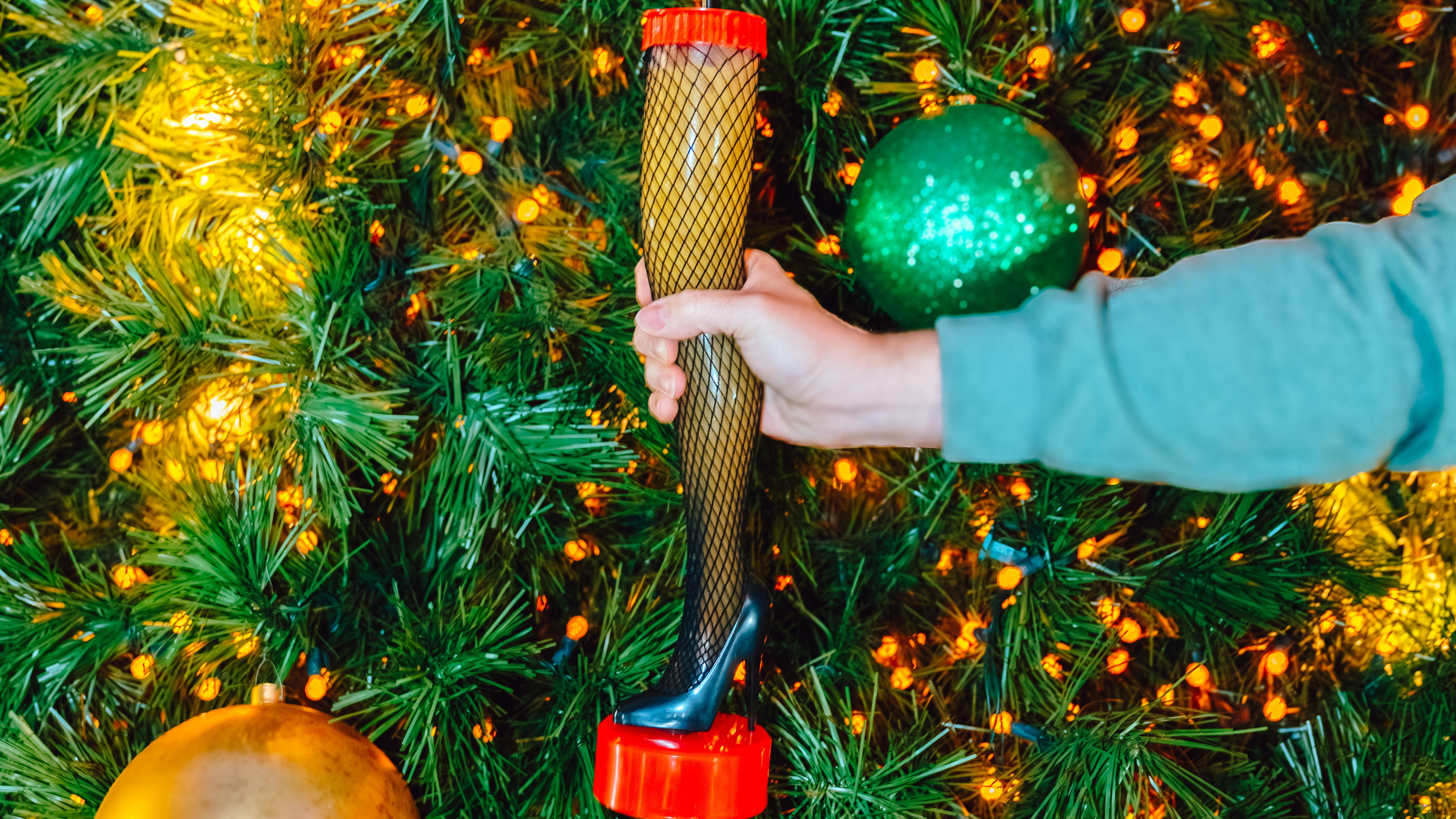Someone holding a leg lamp drink in front of a Christmas tree.