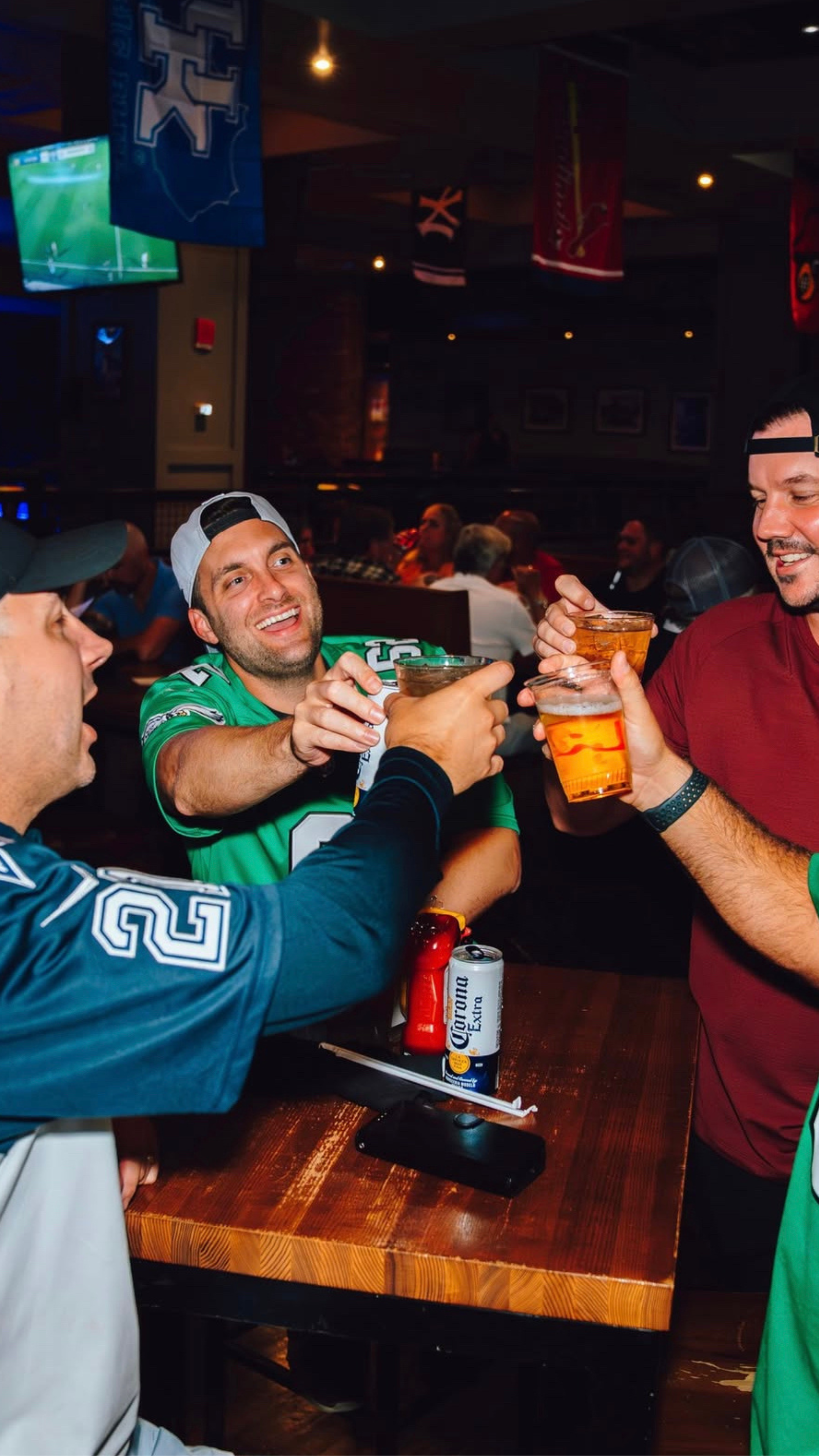 4 men in football jerseys, cheering their beers.