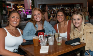 Group of four women enjoying happy hour at Sports & Social Club.