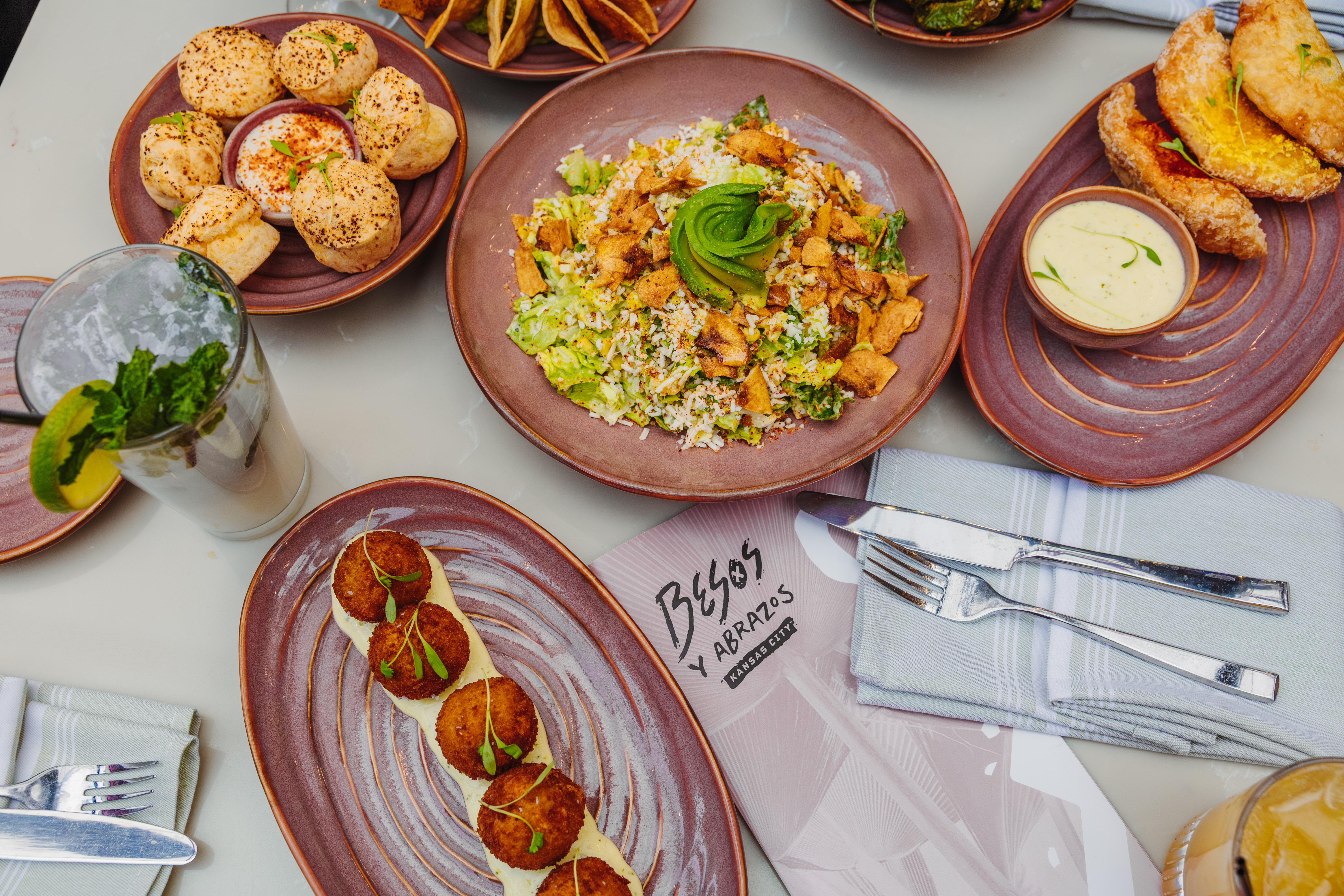 A table spread with appetizers and shareable meals at Besos Y Abrazos