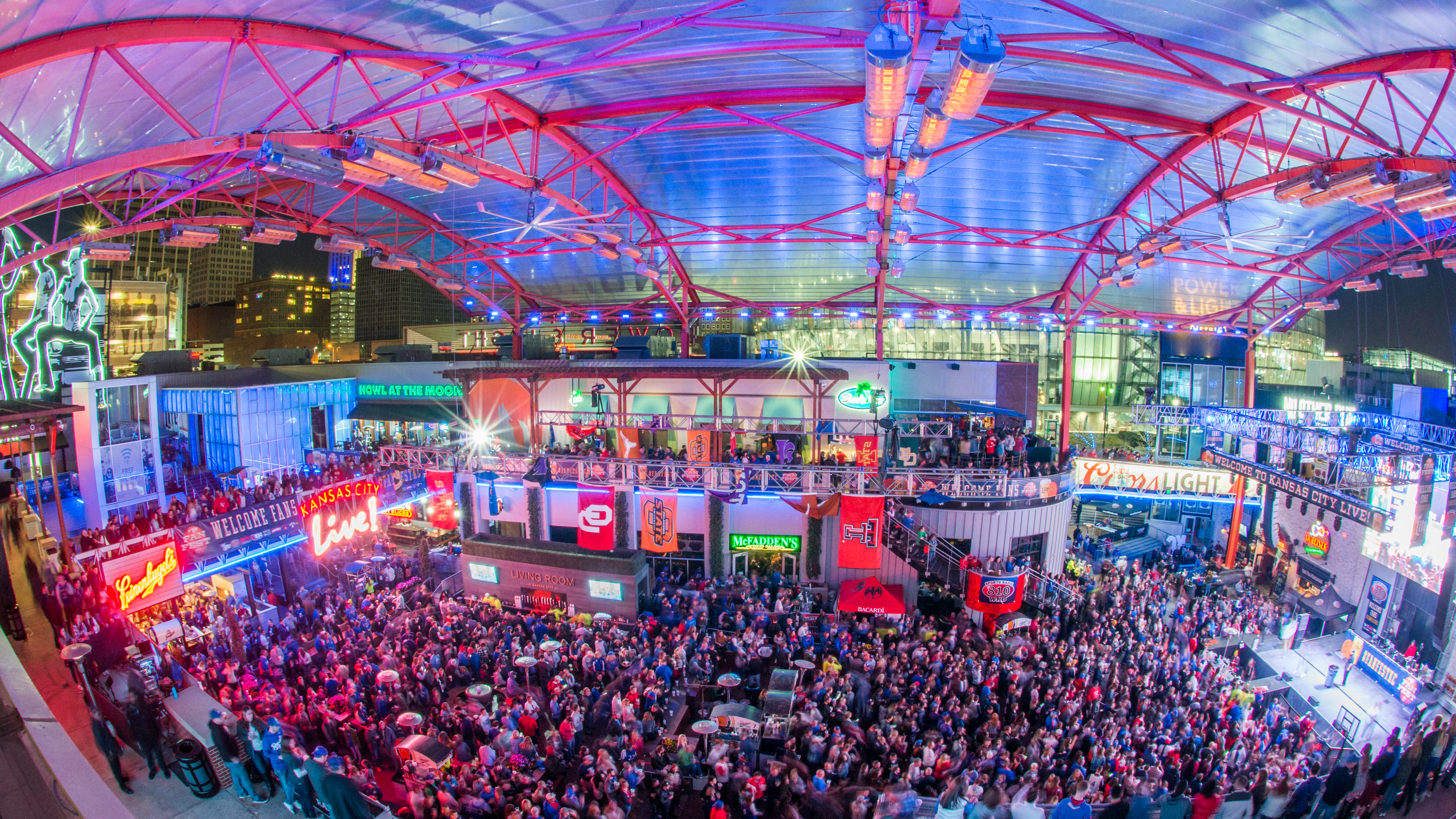 A packed concert venue is colorfully light with blues and reds.