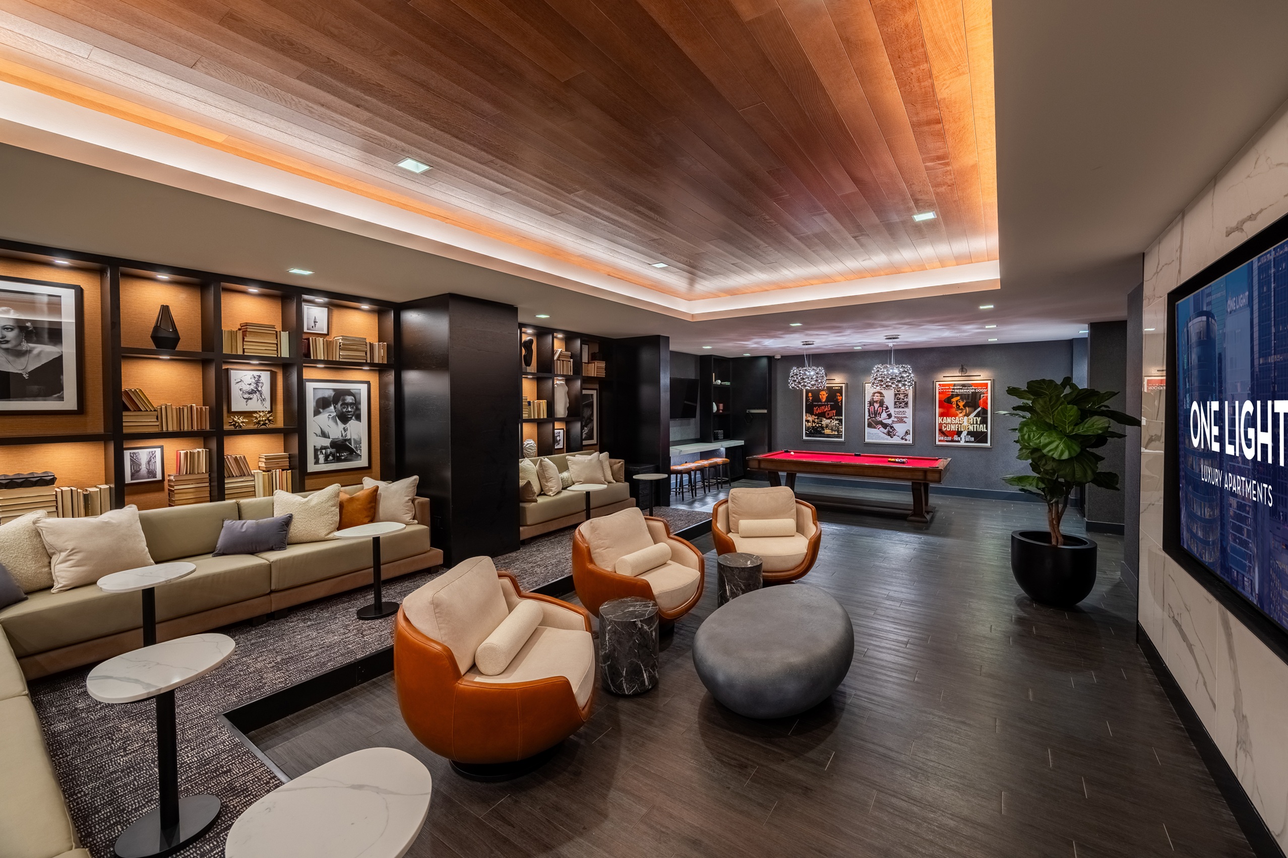 Large screen TV on wall and viewing area with chairs and couches at One Light luxury apartment building.