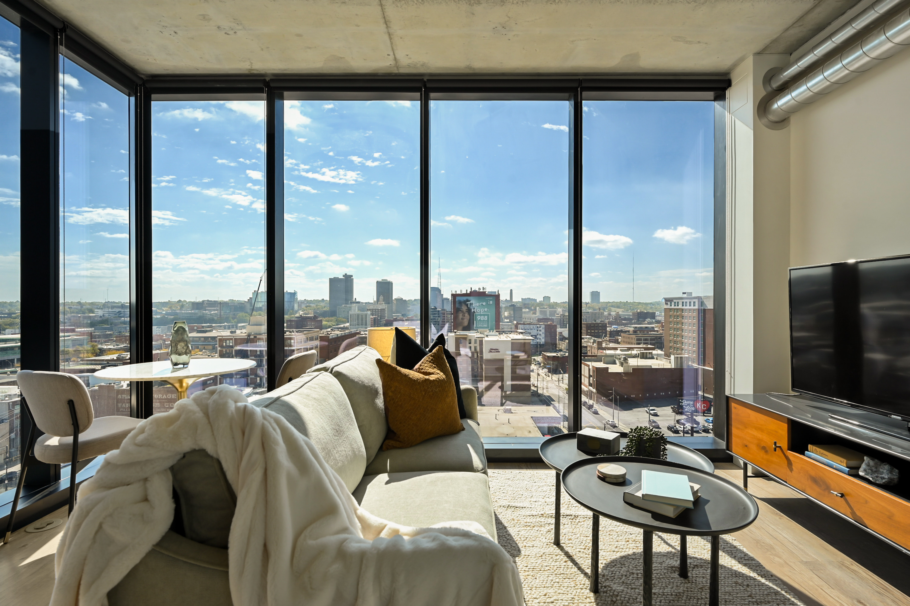 Furnished living room with floor to ceiling windows at Three Light luxury apartments.