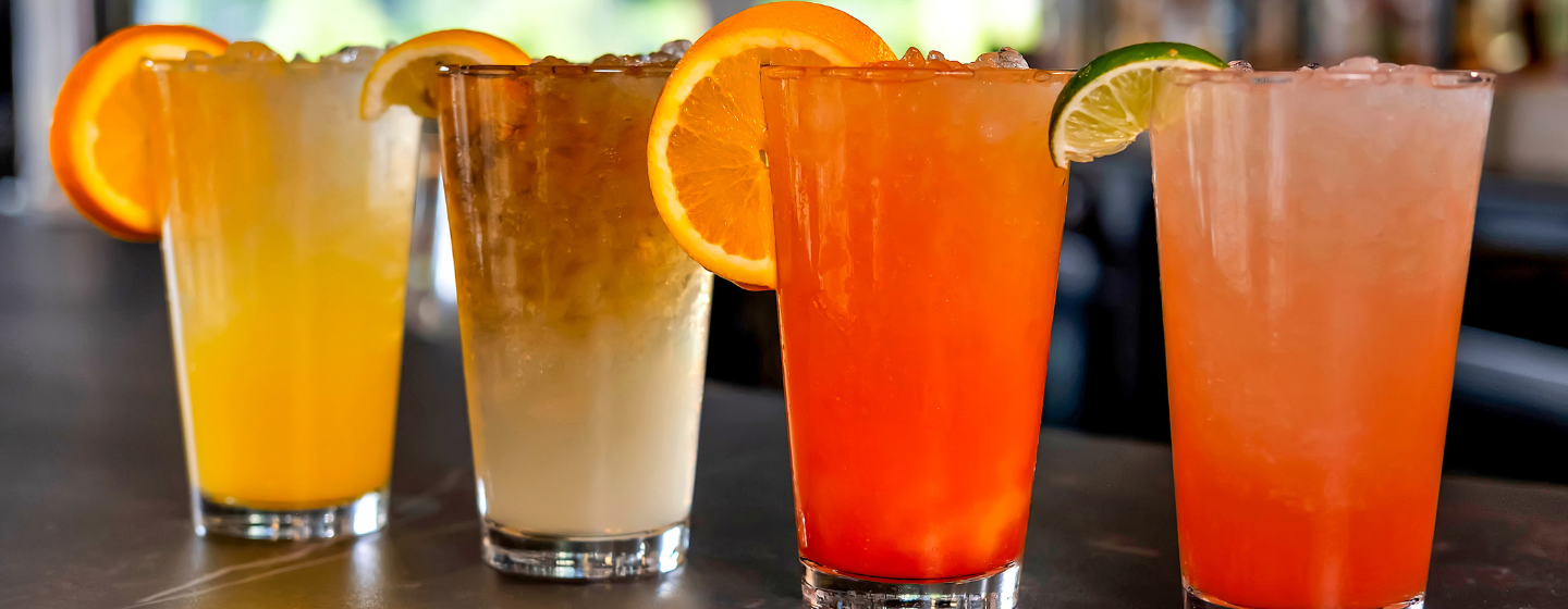 Four signature crush cocktails lined up on the bar at Sports & Social.