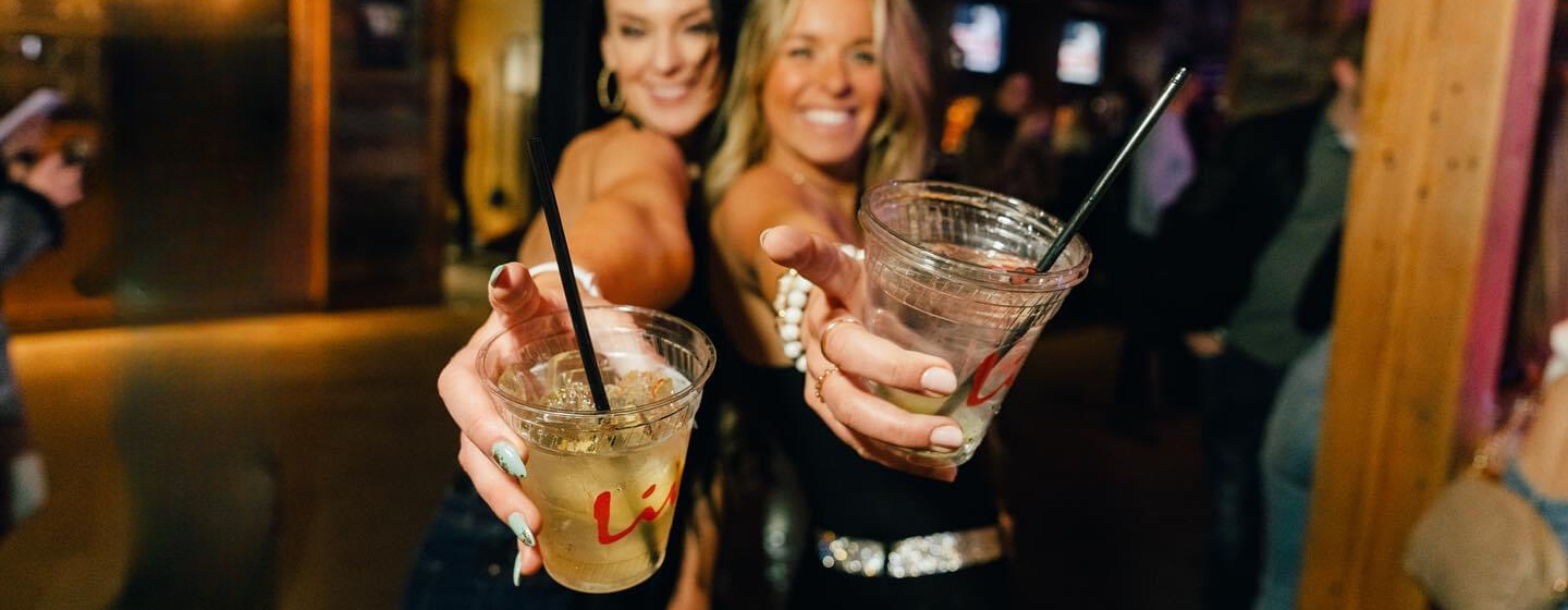 Two women with cocktails at PBR Cowboy Bar.