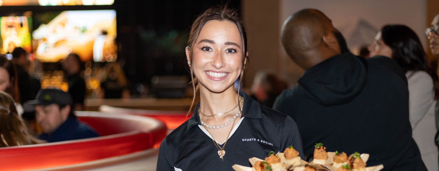 Sports & Social waitress holding tray of food.