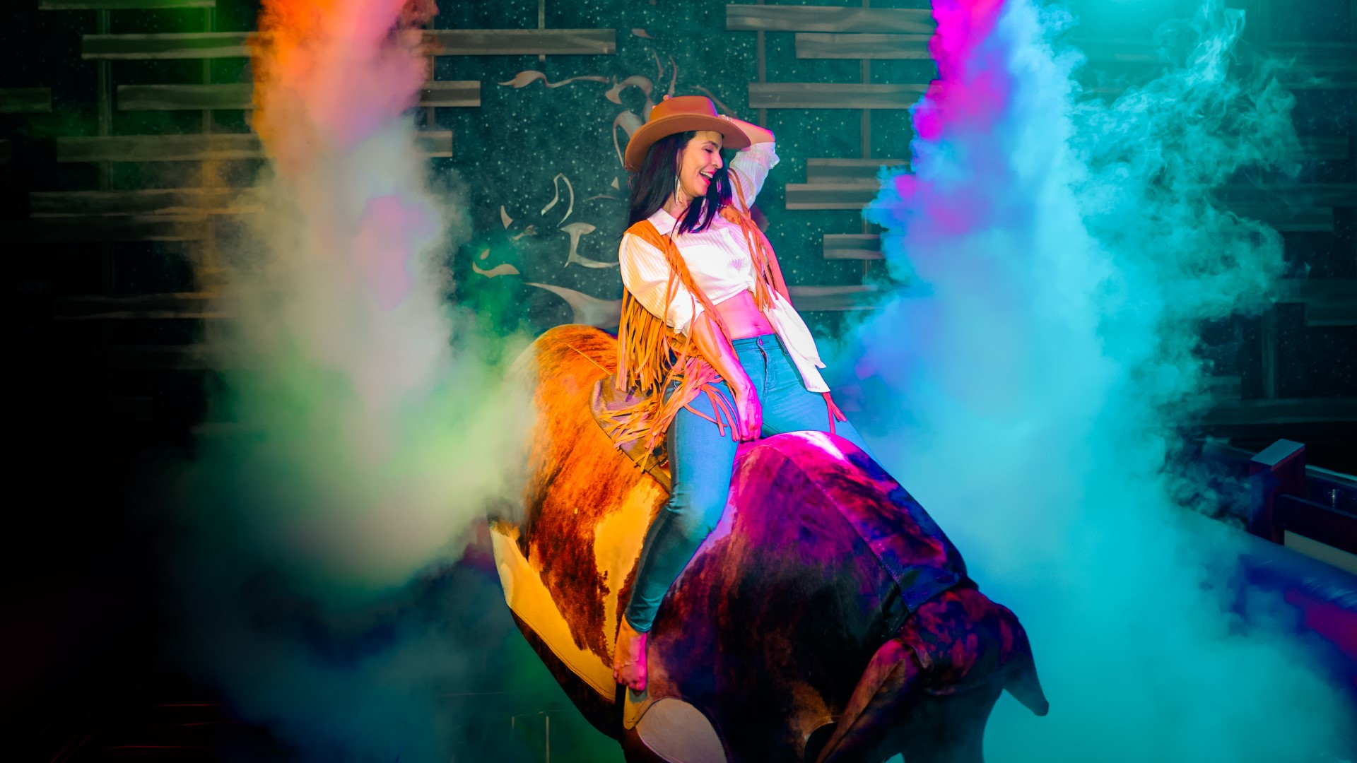 Woman riding the mechanical bull at PBR Cowboy Bar at Live! at the Pointe Orlando.