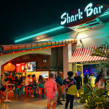Guests entering Shark Bar and sitting at the outdoor patio bar at night.