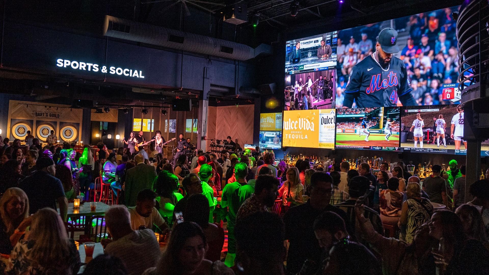 Wide shot of dining area, bar, dart boards, and big screen TVs at Sports & Social at Live! at the Pointe Orlando.