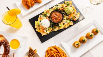 Overhead photo of happy hour food and drink specials including nachos, wings, fries, and large pretzel.