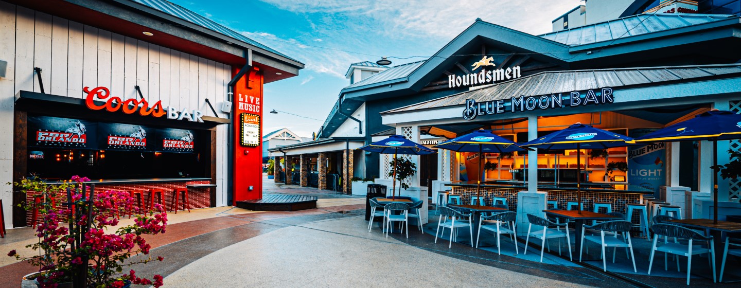 Wide shot of outdoor patios of Live! at the Pointe Orlando including venues and signage - PBR Cowboy Bar, Houndsmen Lounge, and Blue Moon Bar.