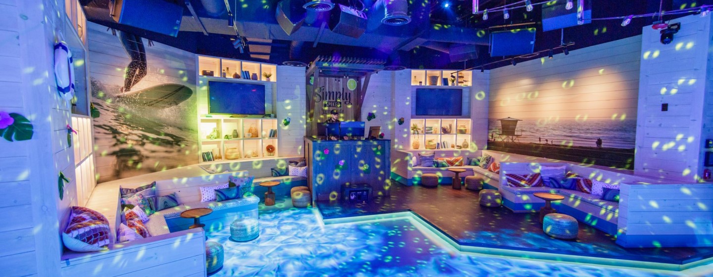 Dance floor, DJ booth and seating area with colorful strobe lighting to simulate underwater feeling at Shark Bar at Live! at the Pointe Orlando.