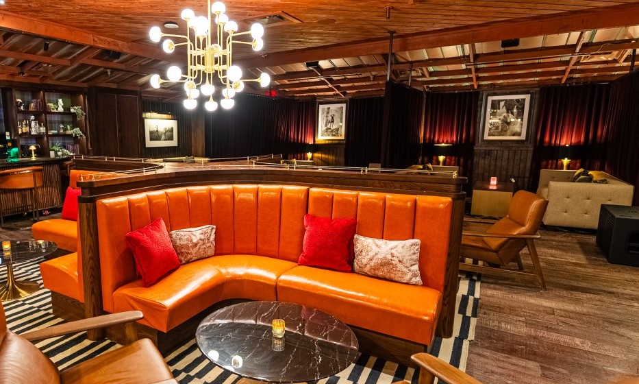 Interior of The Spot By Dre and Snoop featuring orange leather banquets, wood paneled ceiling, and semi-private curtained booths.