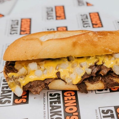 Geno's cheesesteak with cheese and onions on branded wrapper.