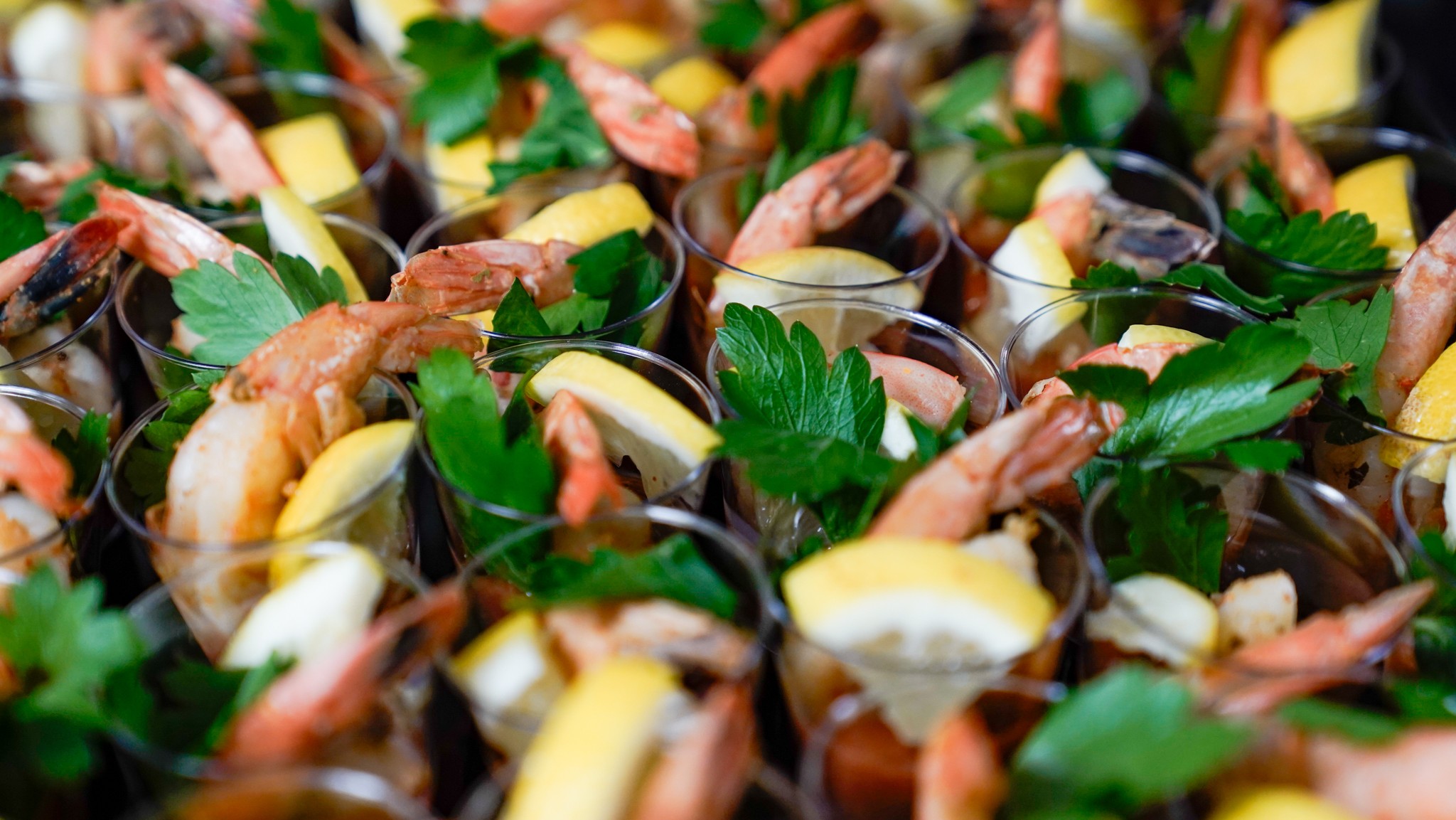 Shrimp hors d'oeuvres in cups with lemon and green garnish.