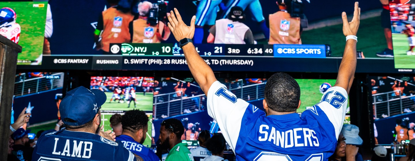 Dallas Cowboys fans watching football game on media wall and big screen TVs at Sports & Social sports bar, Arlington, TX.