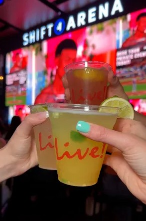 Margaritas in Live! branded cups being toasted in front of jumbo screen at Shift 4 Area at Texas Live!