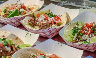 Ground beef soft tacos in red and white checkerboard food trays.